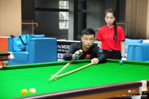 A wheelchair player attempts a long yellow with the rest while the referee looks on over his shoulder