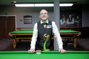 Daniel Blunn poses at the side of the table at the Landywood Snooker Club with his WST Hall of Fame award