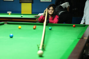 A player plays a snooker shot with the long rest