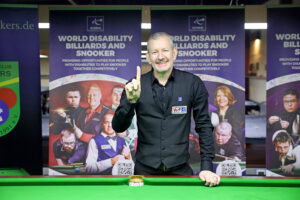 Gary Taylor poses by the table holding up one finger after reaching world number one in the Group 8 rankings