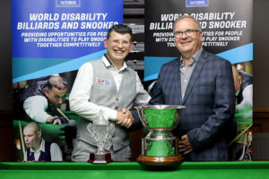 Leroy Williams is presented with the trophy by WDBS Chairman Nigel Mawer QPM after victory at the 2023 Champion of Champions
